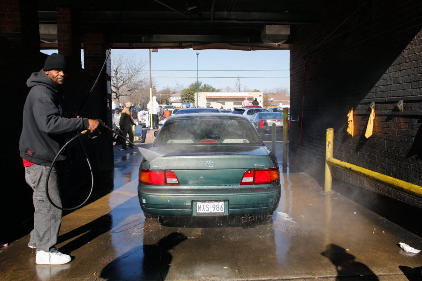 Orece Tasby takes advantage of the crowd by washing spectators' cars for tip money at Jim's...