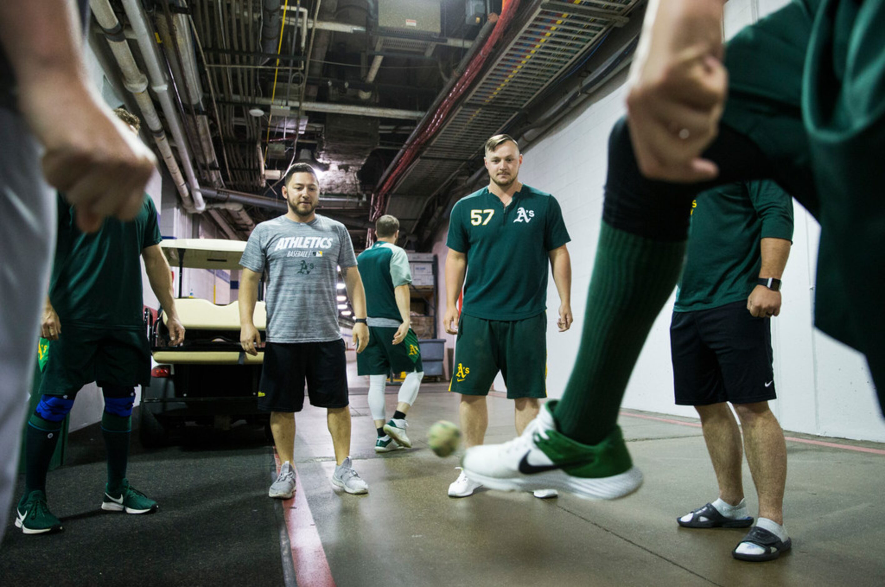 Oakland Athletics players play tacky sack in the tunnel during a rain delay at an MLB game...