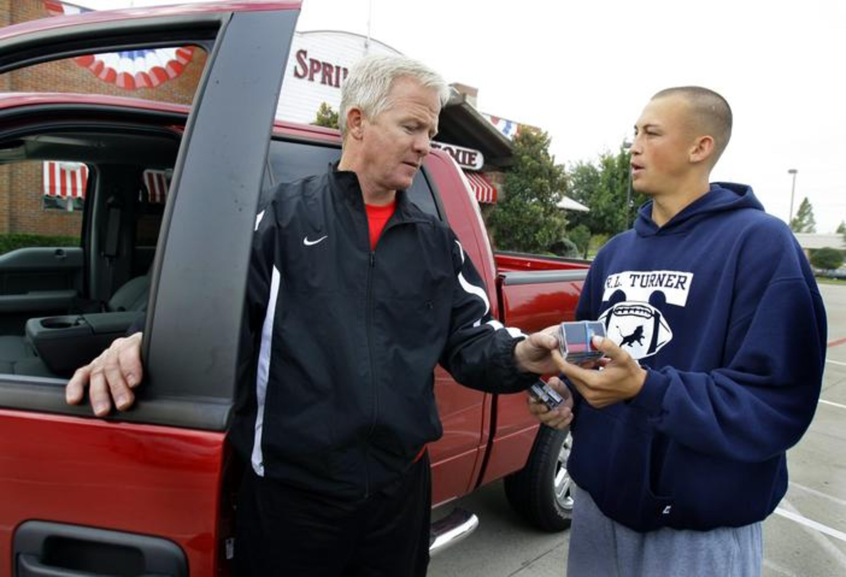 Carrollton R.L. Turner assistant coach Clinton Taylor (right) exchanges game tapes with...