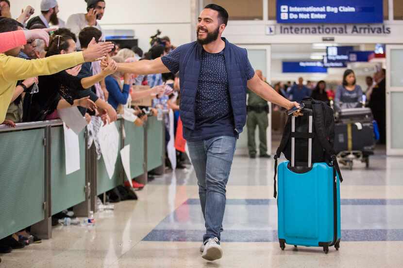 Traveler Alex Galindo high-fives protesters at DFW International Airport holding signs in...