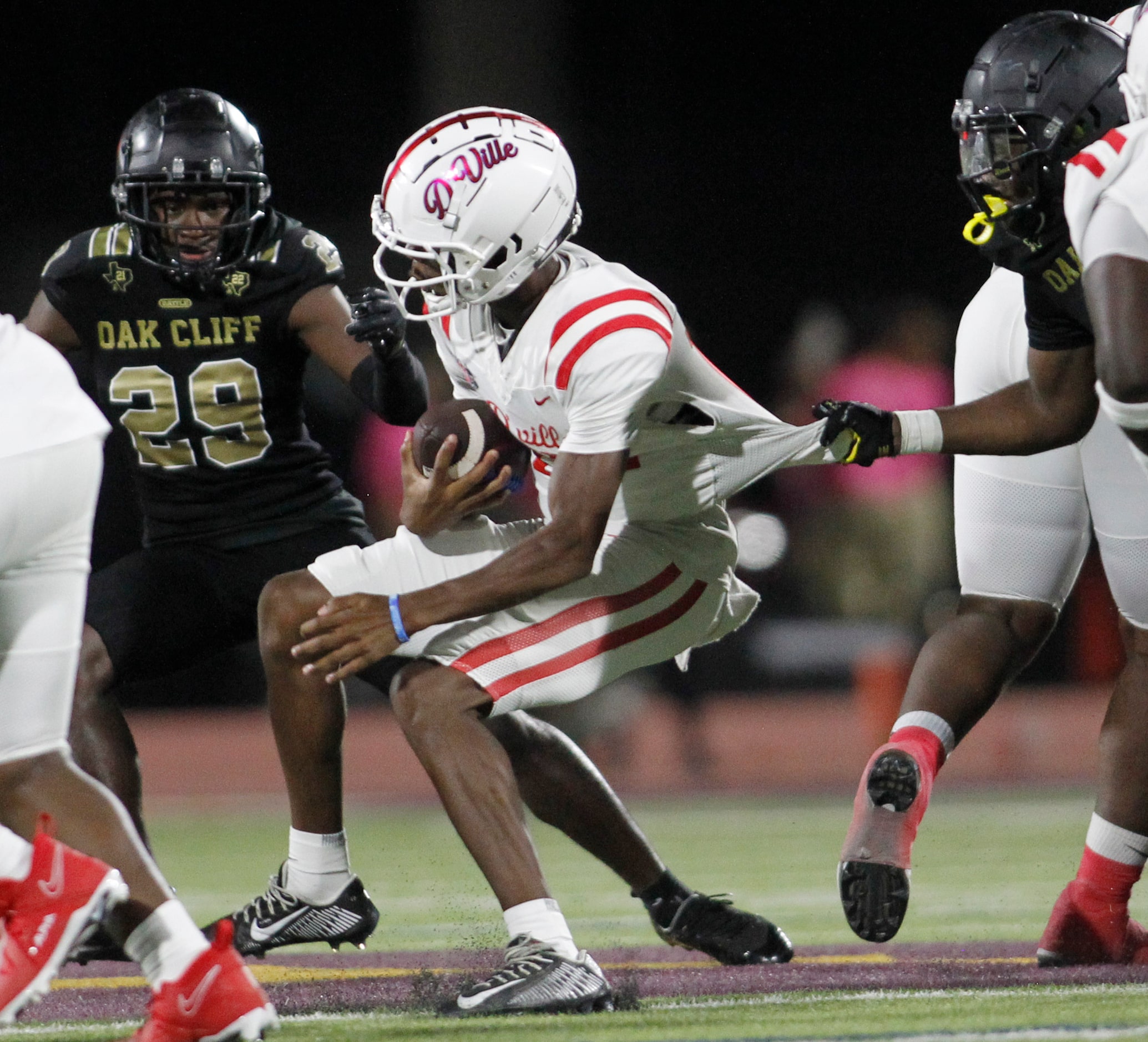 Duncanville quarterback Keelon Russell (12), center, is slowed by South Oak Cliff defensive...