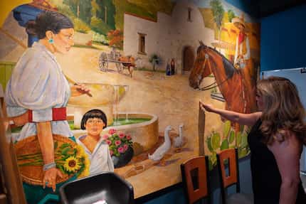 Norma Valles points at smoke damage on a mural that survived a fire in December 2020 at her...