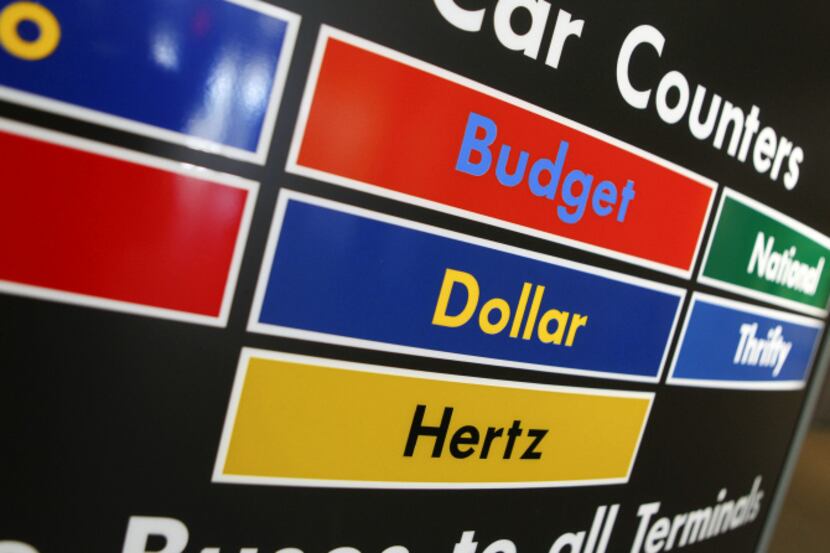 Vehicle rental companies including Hertz, Dollar and Budget are listed on a sign at a...