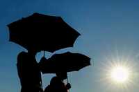 UTD students Jerin Pullan (right) and Naveen Georgi shade themselves with umbrellas as they...