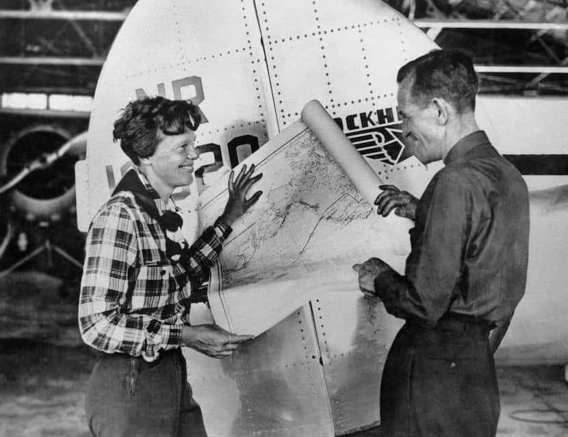 In this undated photo, aviator Amelia Earhart and navigator Fred Noonan pose with a map of...