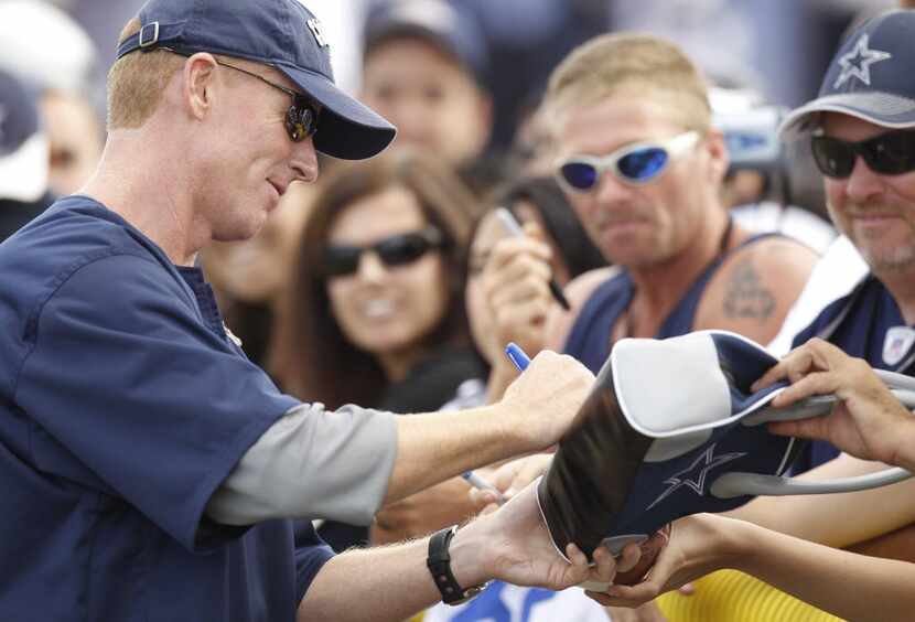 Cowboys offensive coordinator Jason Garrett signs a woman's purse during their afternoon...