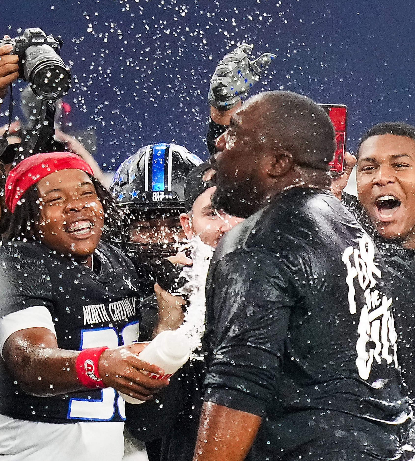 North Crowley head coach Ray Gates is doused by his players, including Boone Harris (left)...