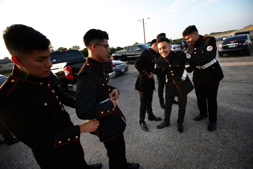Marco Barajas (second from left) gets help from a fellow cadet with his suit. The teens...