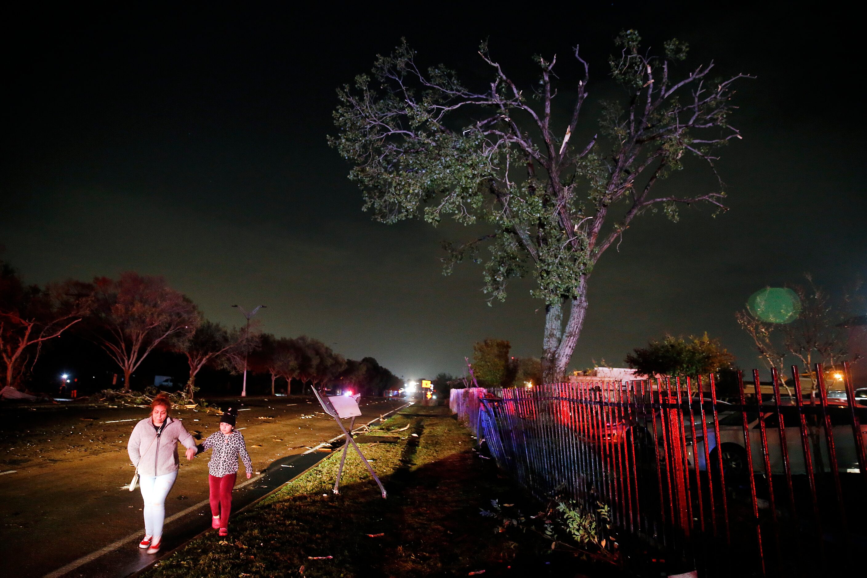 People walk along the debris strewn Pioneer Parkway in Arlington after a tornado-warned...