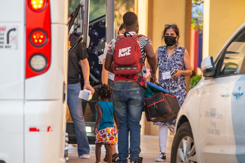 Volunteers with Faith Forward Dallas help migrant families from Haiti and Cuba exit a coach...