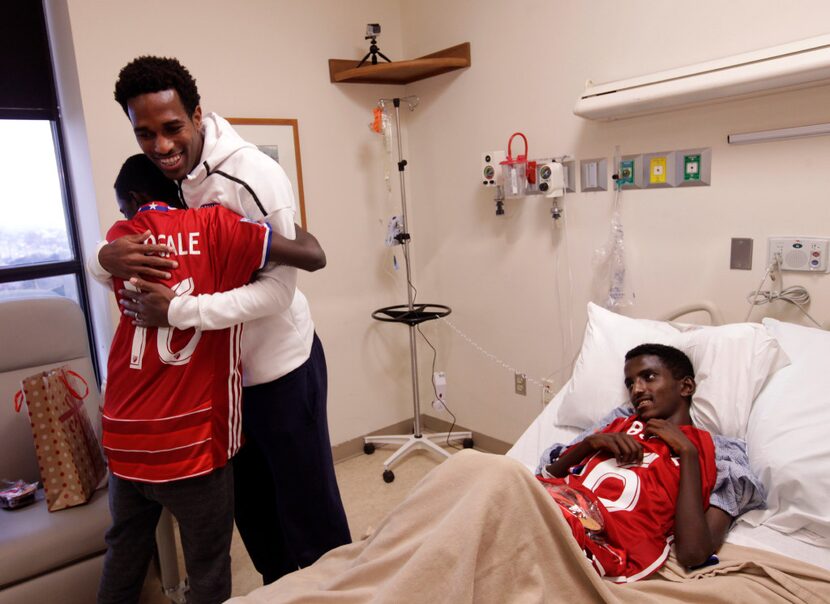 Markos Bogale (left), 16, hugs FC Dallas player Atiba Harris as Tamirat Bogale, 16, watches...