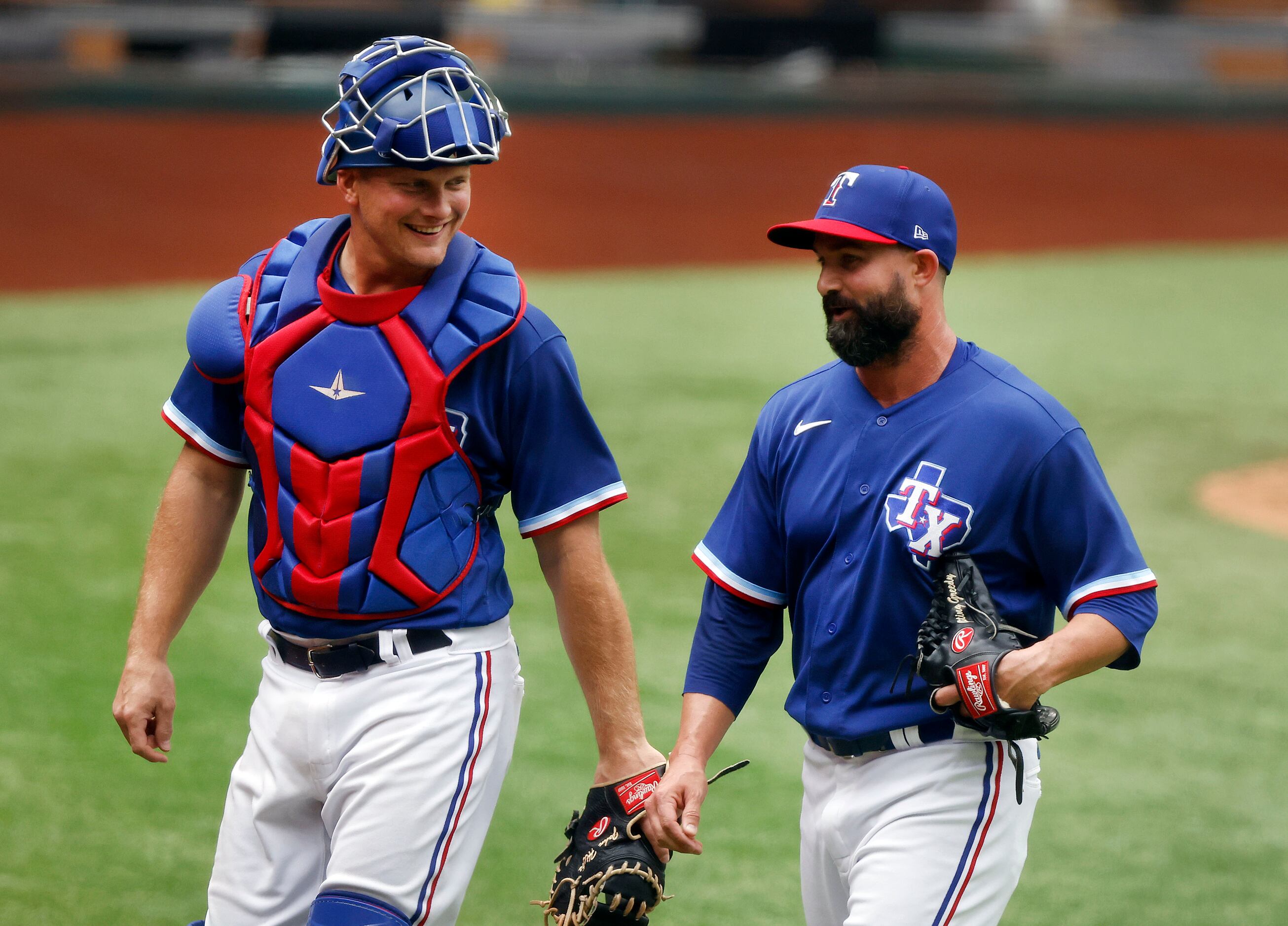 Texas Rangers relief pitcher Nick Vincent and catcher Jonah Heim laugh as they come off the...
