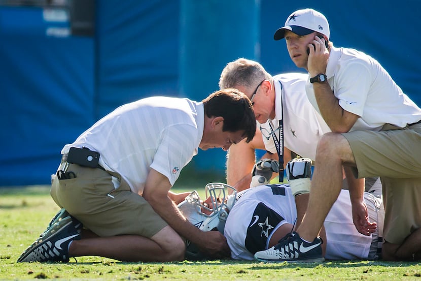 Cowboys guard Zack Martin is checked by trainers after being injured during a joint practice...