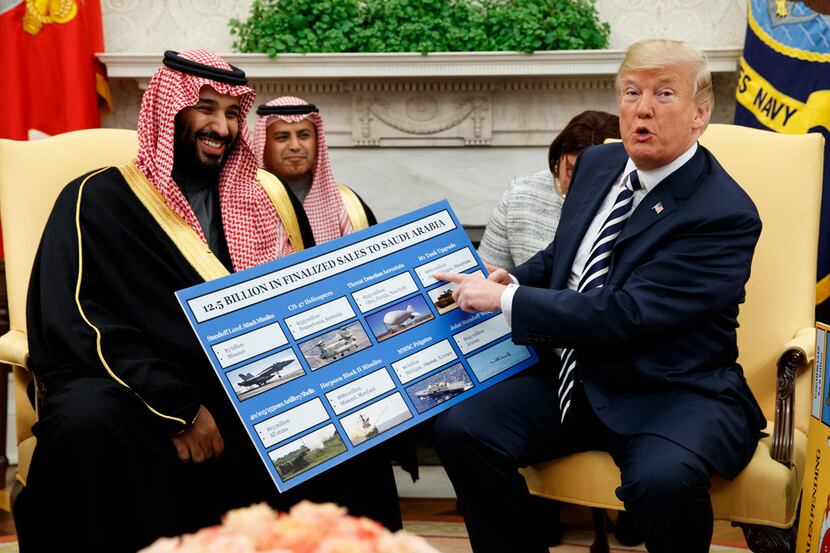 President Donald Trump holds a chart highlighting arms sales to Saudi Arabia during a...