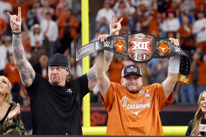 Texas Longhorns quarterback Quinn Ewers (right) hoists the WWE wrestling belt given him by...