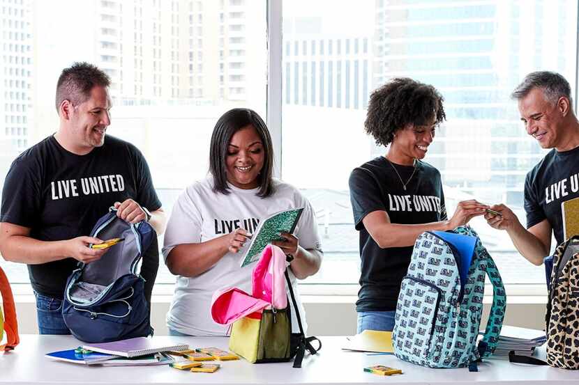 Five people packing backpacks while volunteering with United Way, wearing Live United shirts