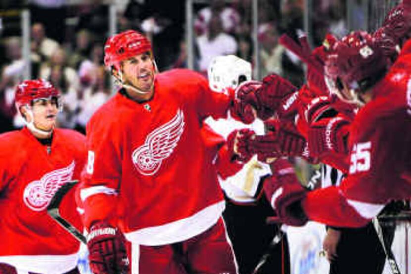  Mike Modano celebrates with teammates (above) after scoring his first goal as a Red Wing in...
