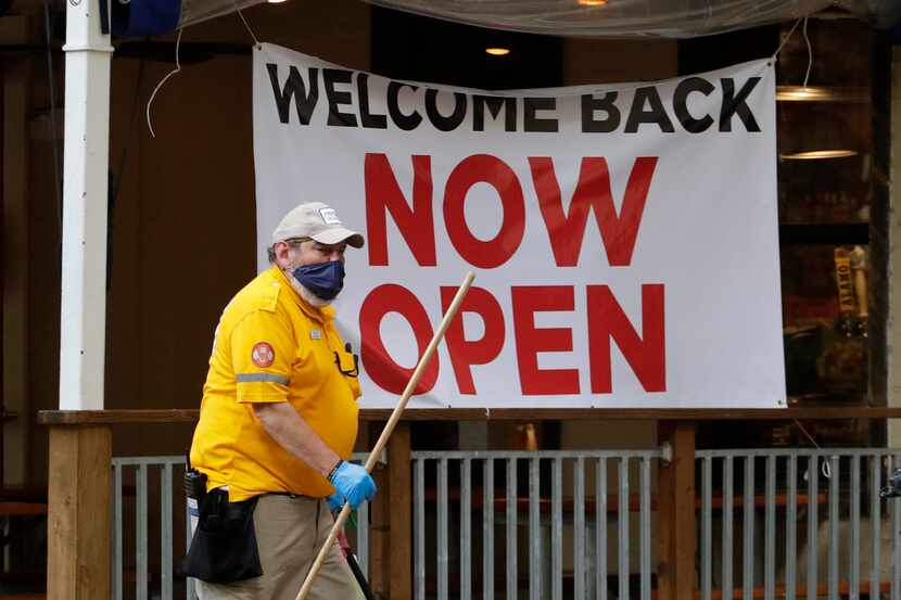 A worker passes a sign at a restaurant along the River Walk that has reopened in San...