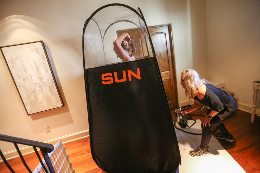 Stephanie Lynch, right, of No Bad Looks, sprays Courtney Newell in her home on Friday, April...