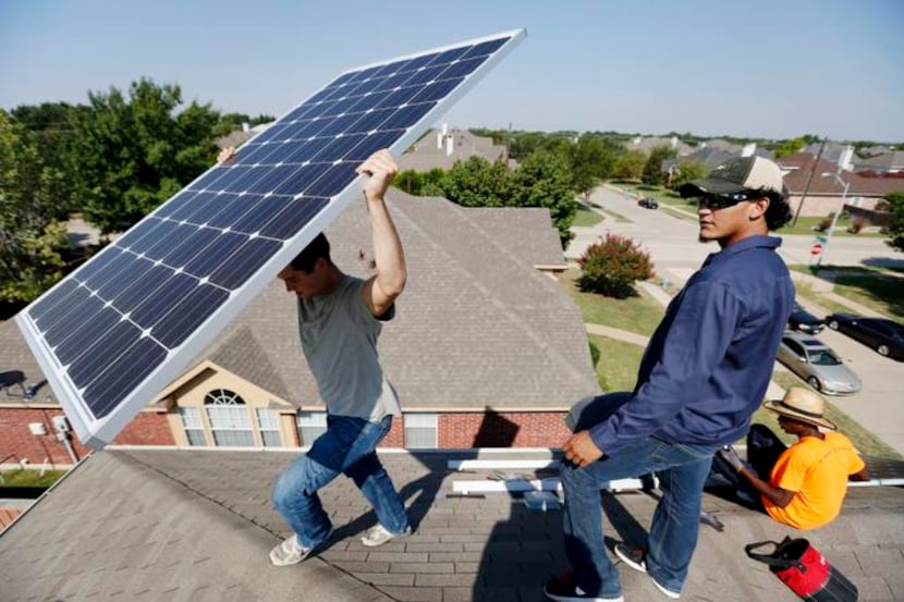 
Michael Perdue (left) lifts a solar panel as Michael Garcia (center) and Jade Anderson...