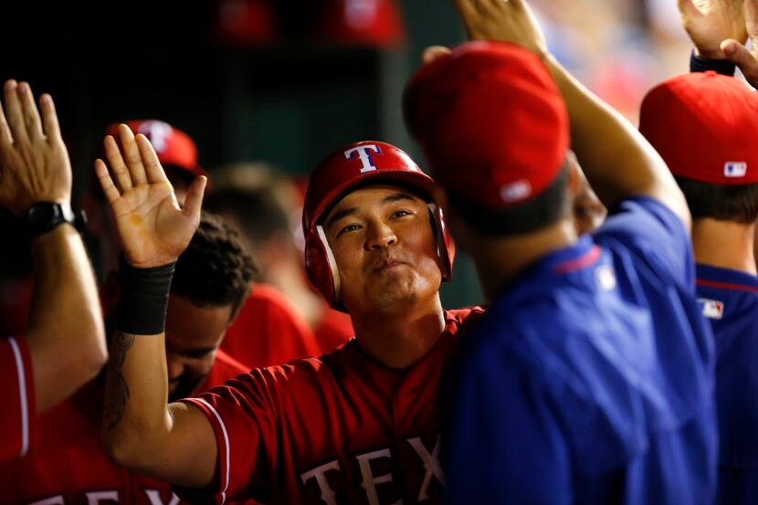 Texas Rangers right fielder Shin-Soo Choo (17) is congratulated in the dugout by teammates...