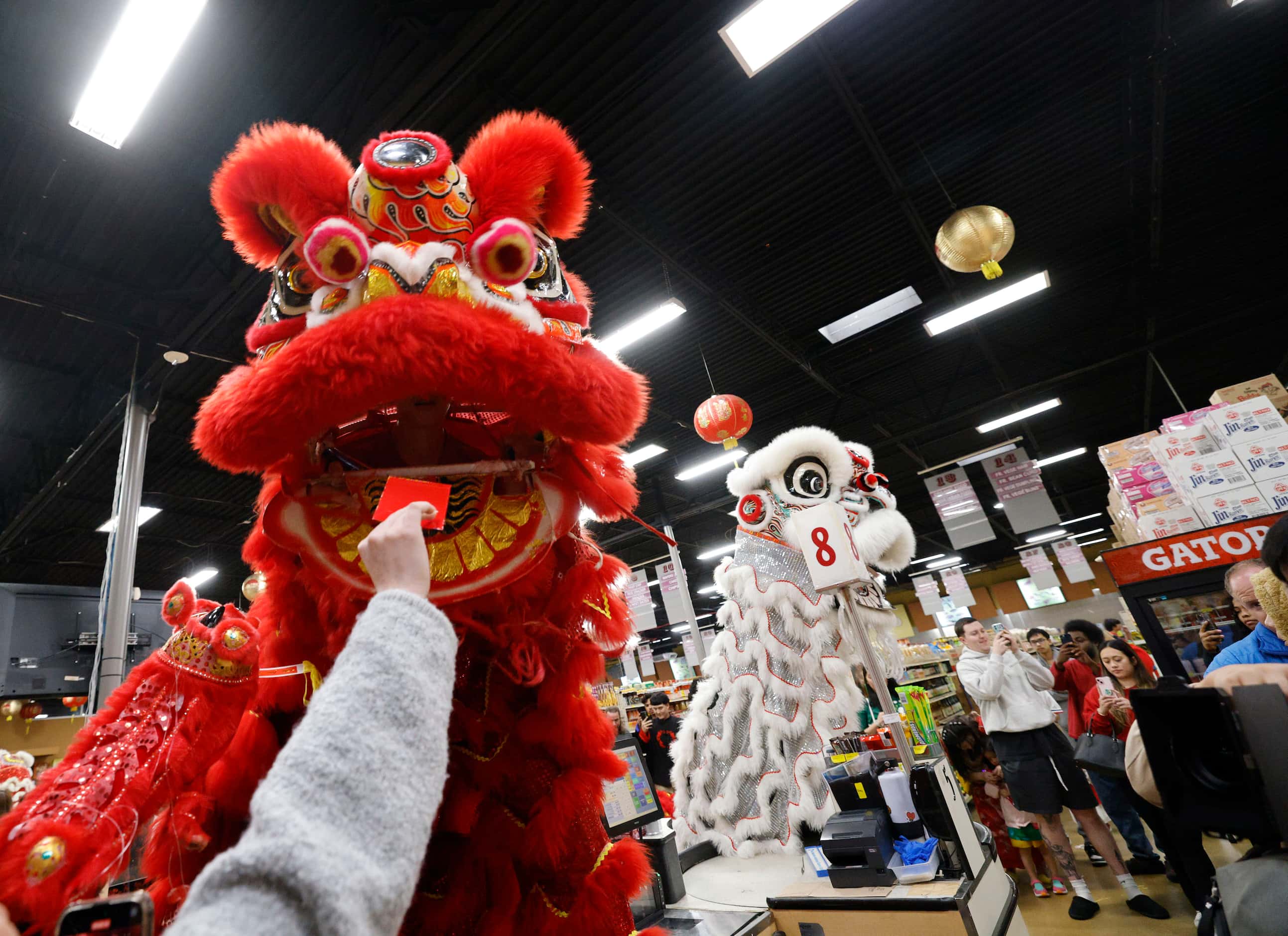 Lion dancers from GDPT Phap Quang receive a red envelope as they perform inside a...