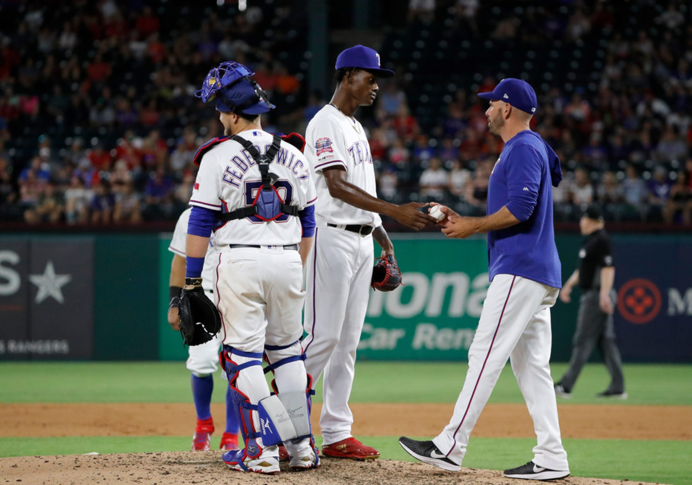 Texas Rangers' Tim Federowicz stands on the mound as relief pitcher Phillips Valdez turns...