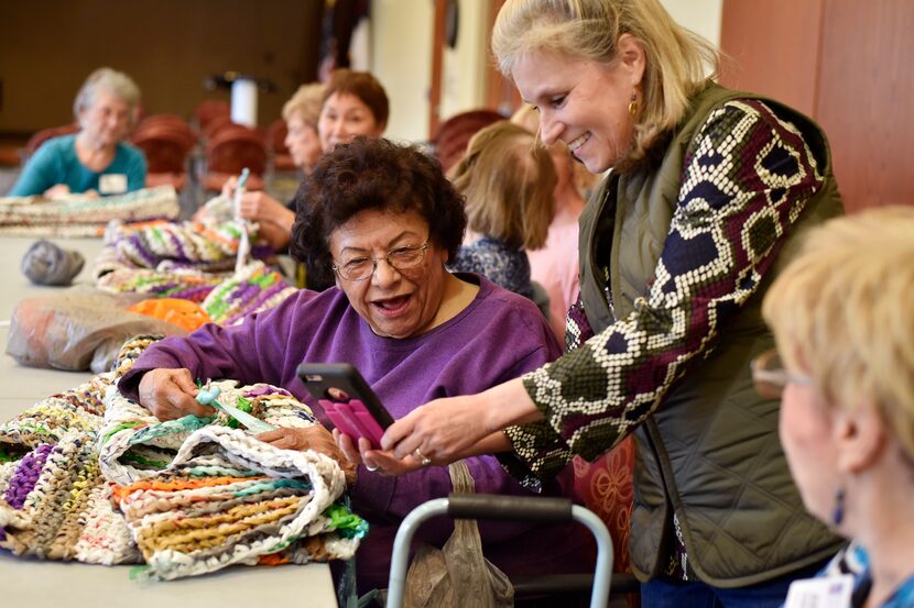 Volunteers Annie Palacios (left) and Brianna Brown look at a photo on Brown's cellphone as...