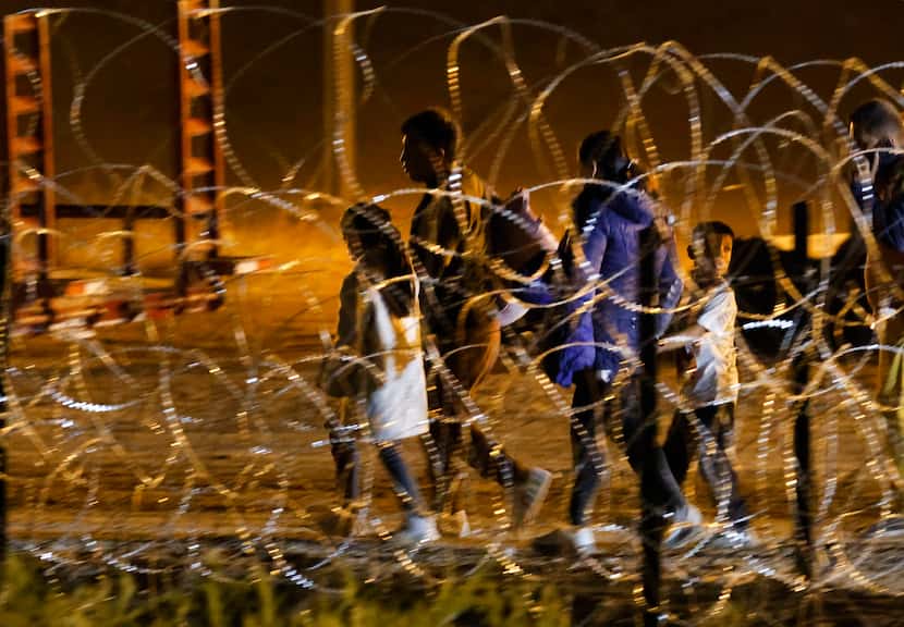 A migrant family makes their way out of the waiting areas behind concertina wire on the U.S....