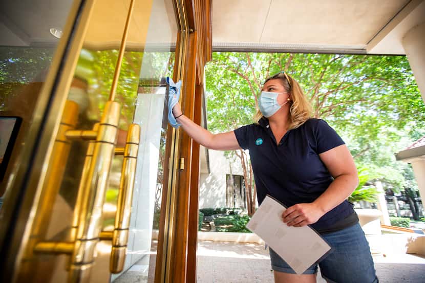 Director of Rooms Kelly Theus wipes down the front door at the Omni Las Colinas Hotel on...