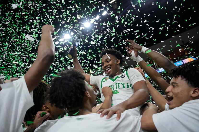 North Texas' Tylor Perry (5) holds up the trophy while celebrating with teammates after...