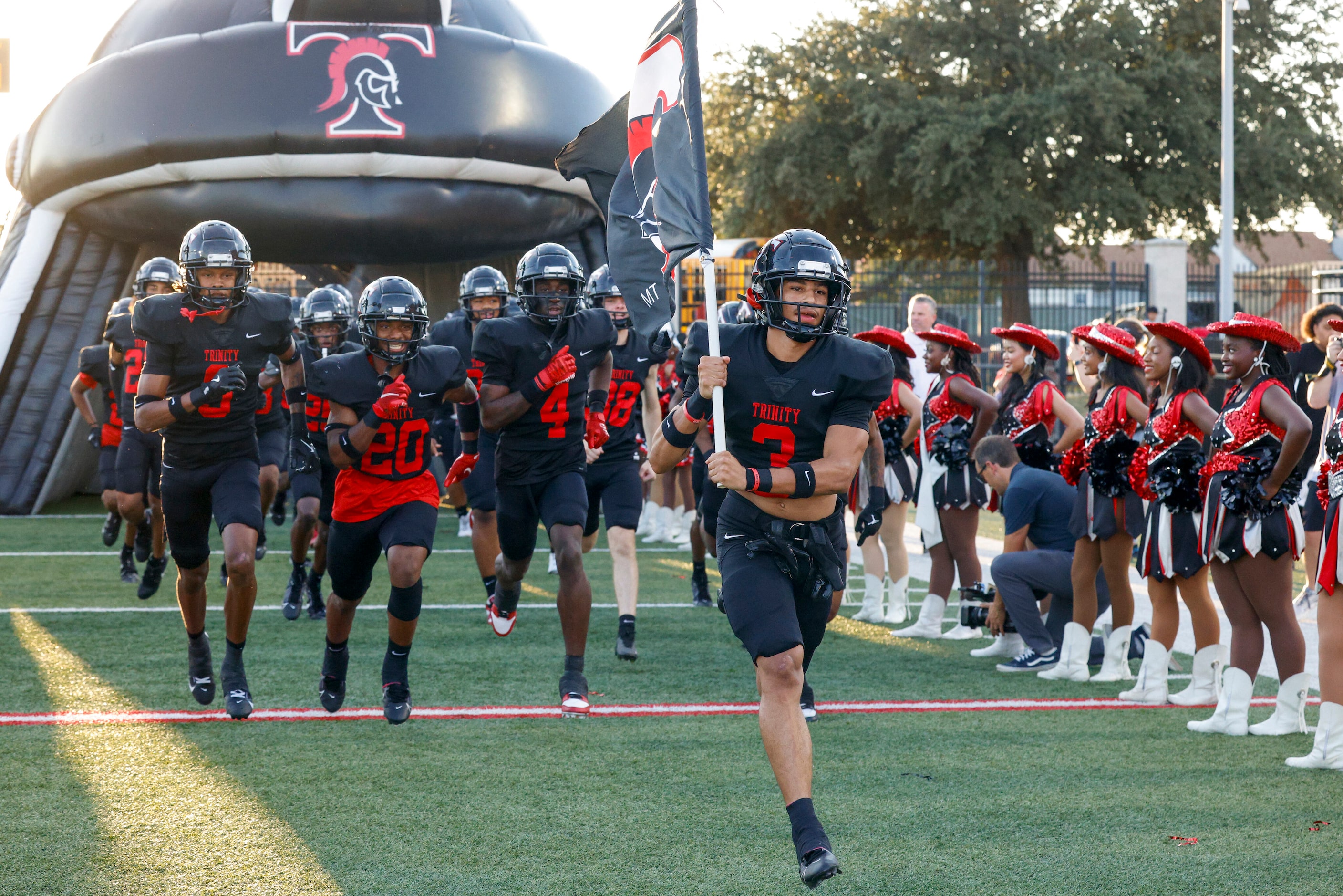 The Euless Trinity football team takes the field before the first half of a District 4-6A...