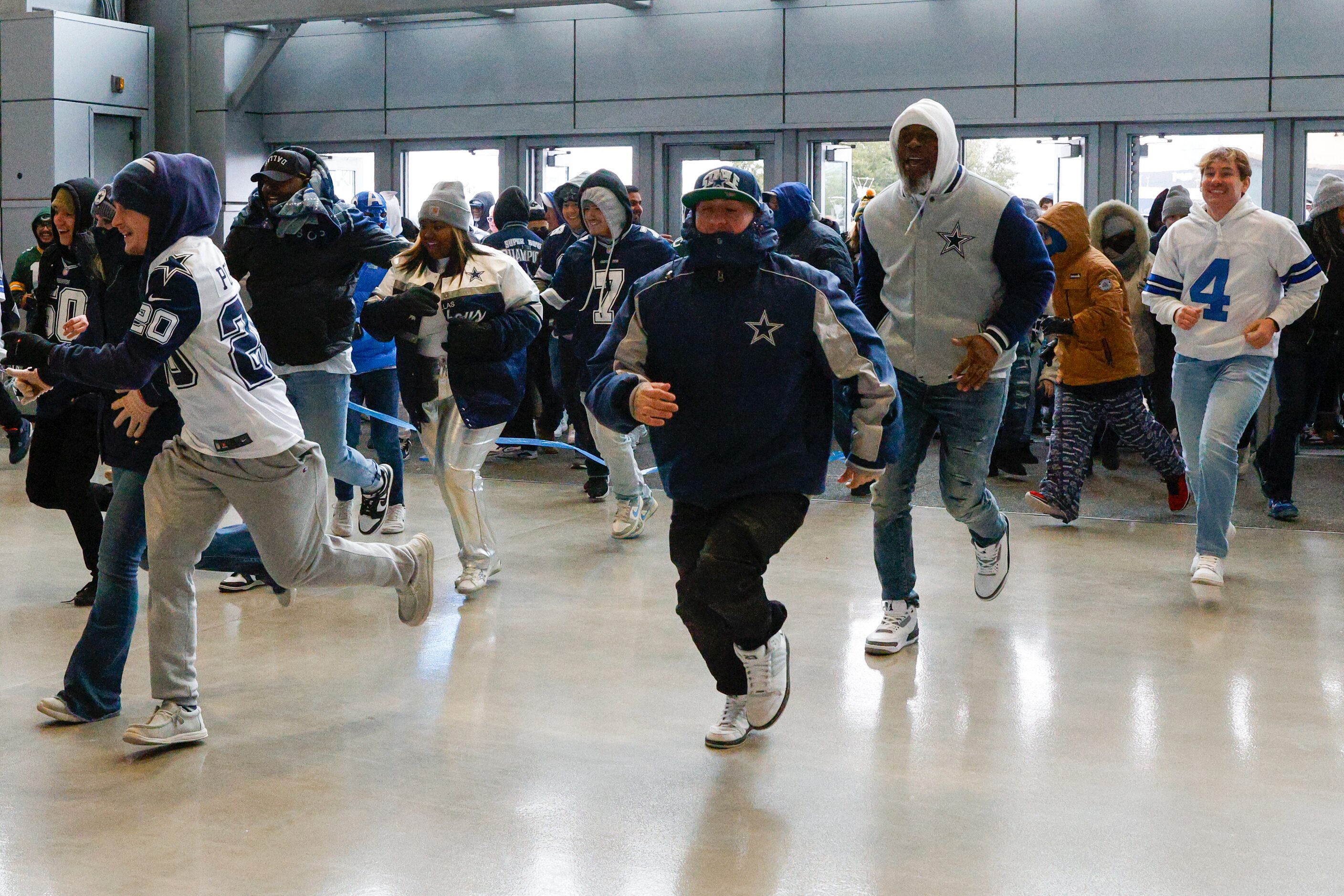 Fans run to claim standing room only spots before an NFL wild card playoff game between the...