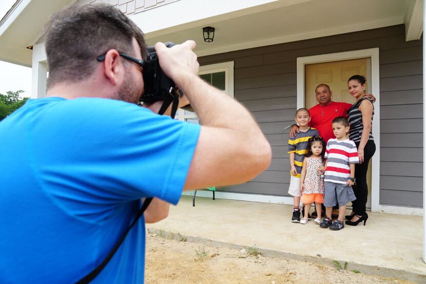 Brian Wolowicz photographs new homeowners Jose Campos, his wife Francisa and their children...