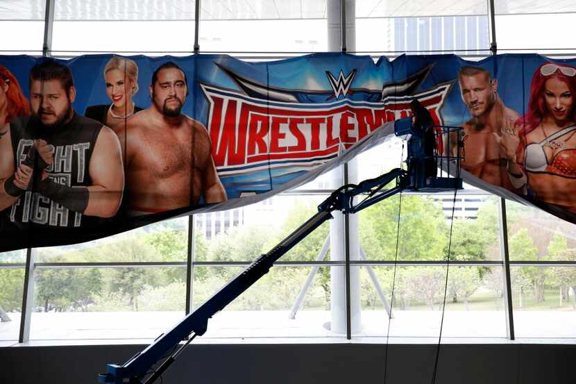 A worker installs a sign for WrestleMania Axxess.