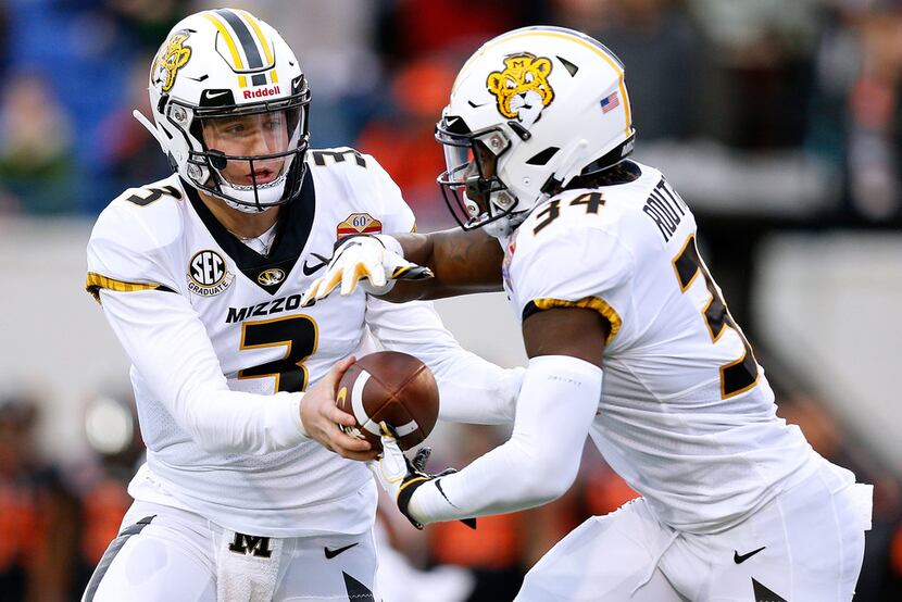 MEMPHIS, TENNESSEE - DECEMBER 31: Drew Lock #3 of the Missouri Tigers hands the ball to...