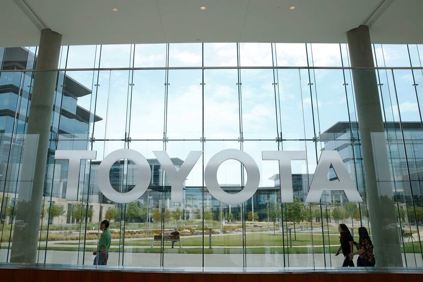 Toyota employees walk by the lobby area at Toyota Motors North America in Plano in this file...