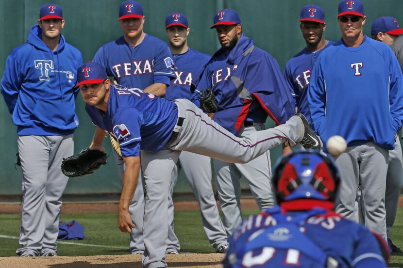Texas pitcher Martin Perez warms up in the bullpen under the watchful eyes of teammates, and...