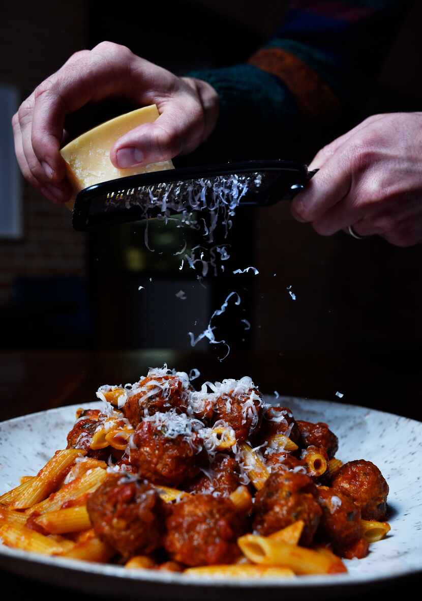 Cheese is shredded on pasta with meatballs and red sauce from Nonna Italian restaurant in...