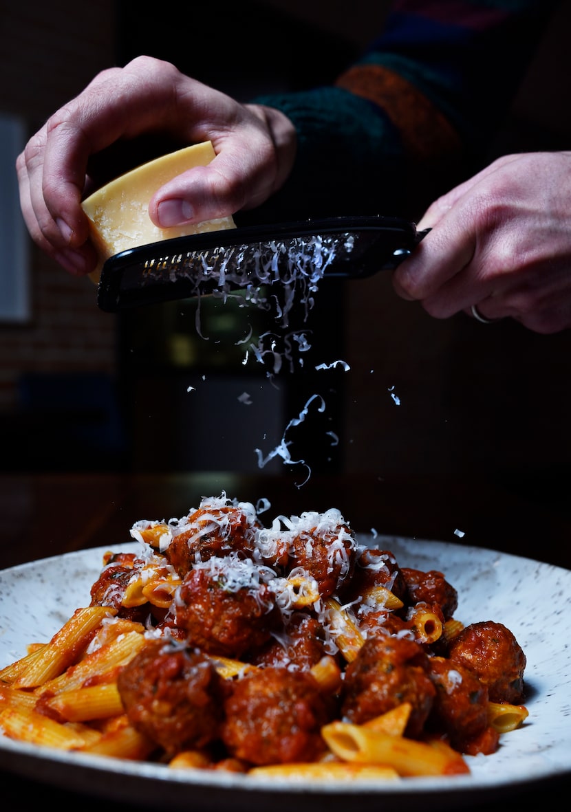 Cheese is shredded on pasta with meatballs and red sauce from Nonna Italian restaurant in...