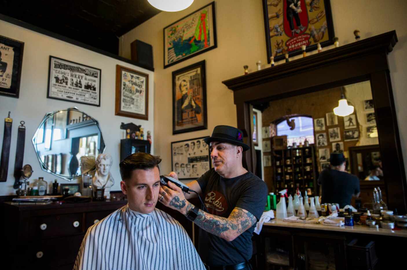 Barber Rob Villarreal, right, gives a hair cut to Andrew Pratt at Rob's Chop Shop across the...
