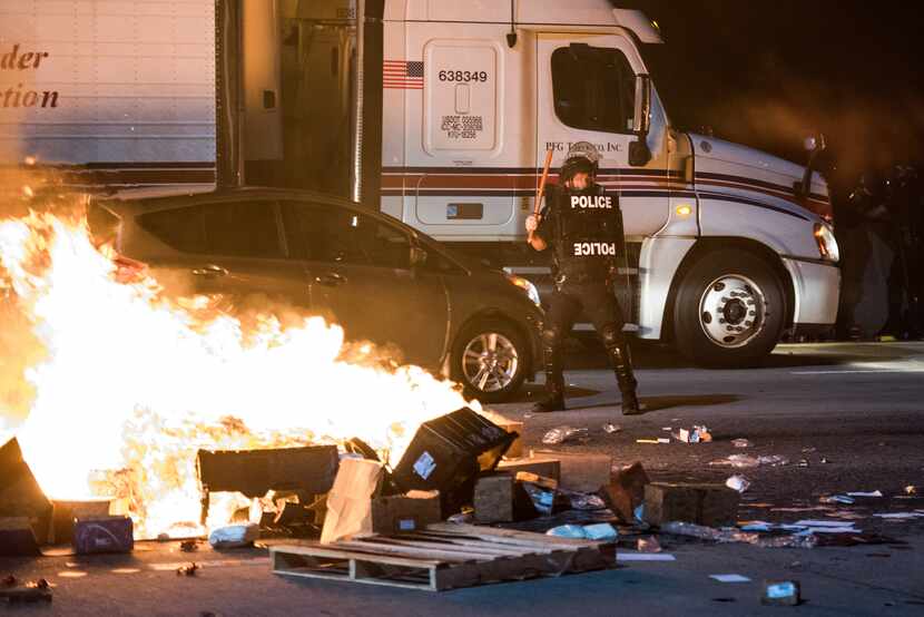 A police officer stands guard near a fire set by protestors on I-85.