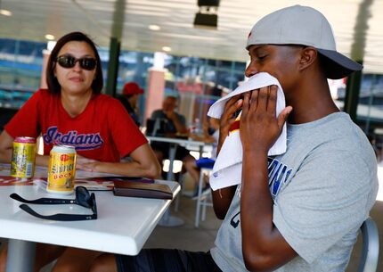 Cleveland Indians fan Herbert Littlejohn of Saginaw, Texas, wipes his face with a wet towel....