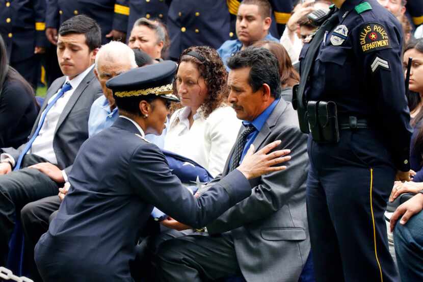 Dallas Police Chief U. Renee Hall hands a folded flag to Rogelio Santander Sr., father of...