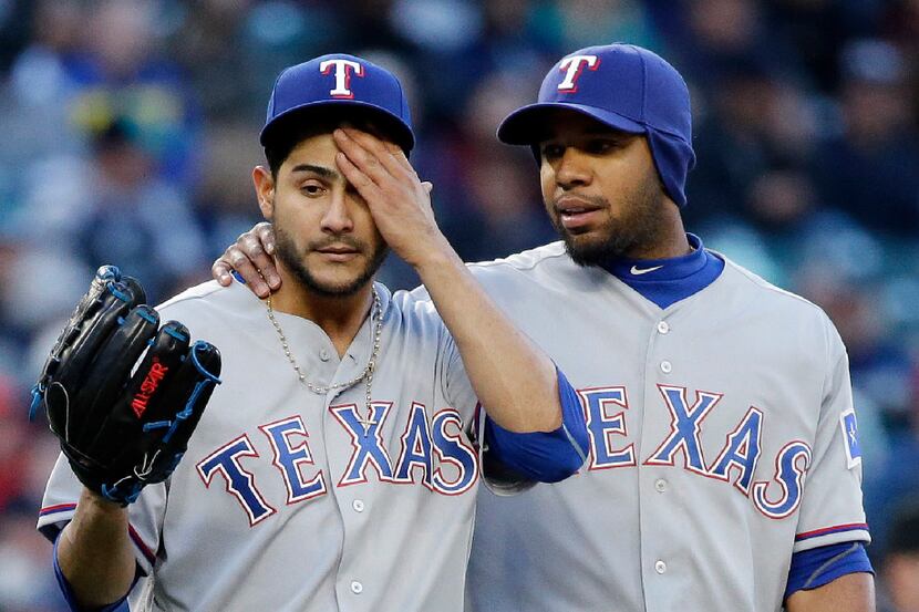 Texas Rangers shortstop Elvis Andrus, right, throws an arm around starting pitcher Martin...