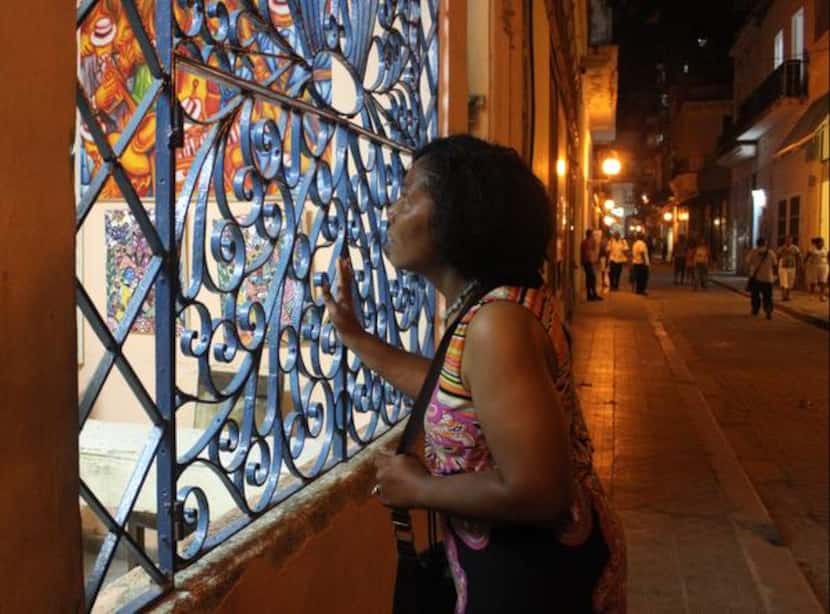 
Credo Choir member Mattie Jette peers at the art in a Havana storefront.
