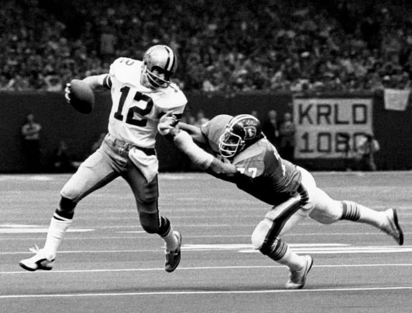 Dallas Cowboys Hall of Fame quarterback Roger Staubach tries to avoid being sacked by Denver...