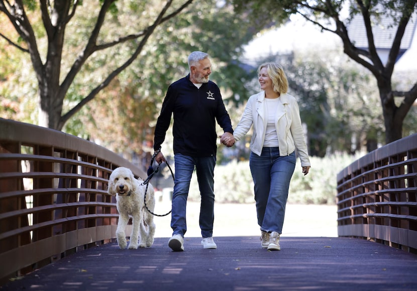 Tad Carper, left, and Ann Carper take Atticus for a walk at the park near their home in...