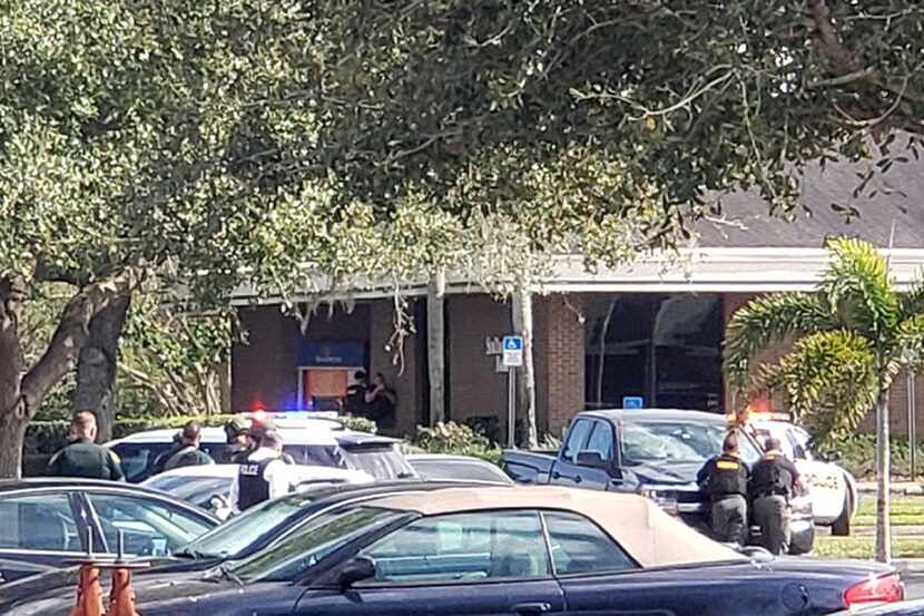Law enforcement officials take cover outside a SunTrust Bank branch Wednesday in Sebring, Fla.