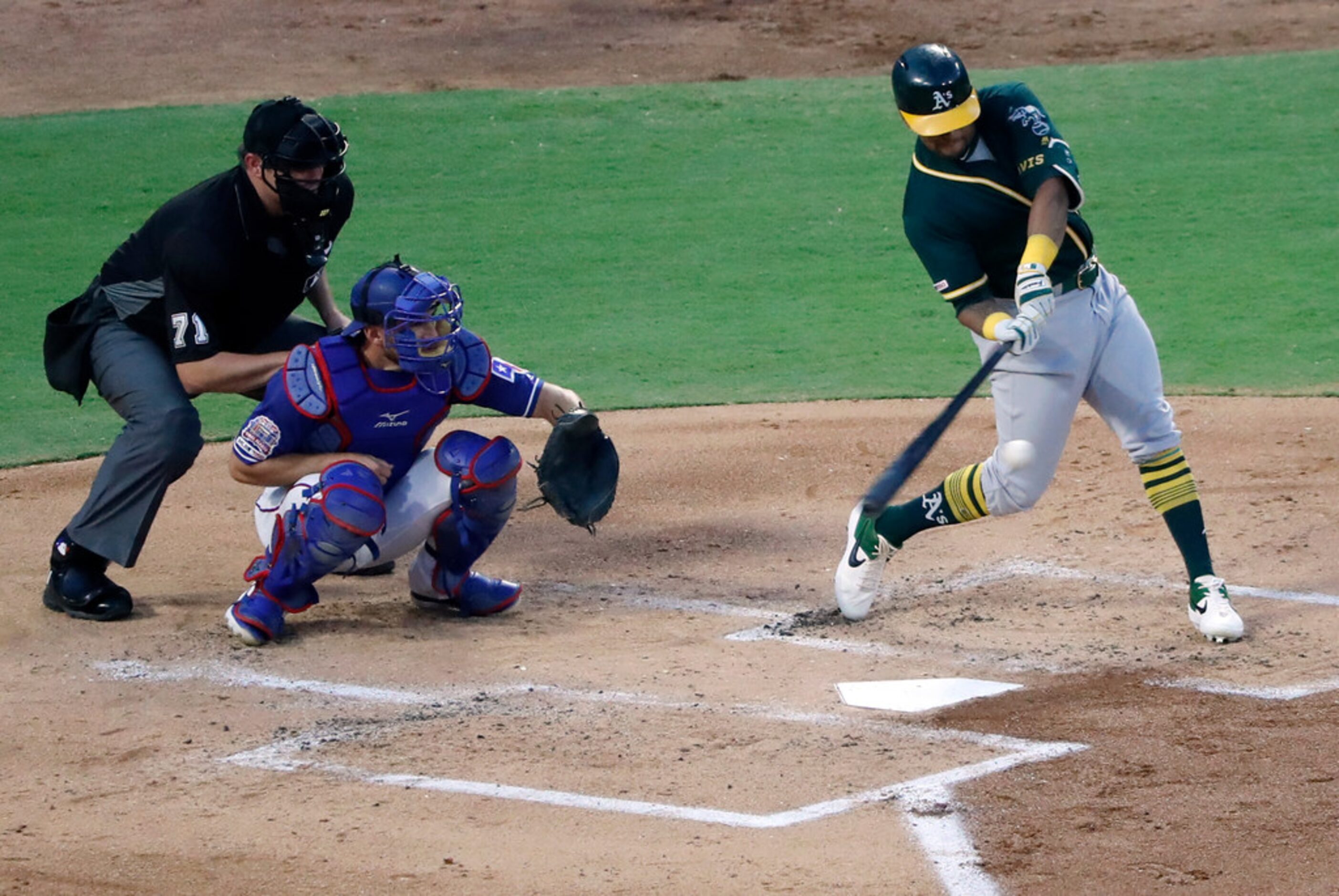 Umpire Jordan Baker, left, and Texas Rangers catcher Jeff Mathis, center, look on as Oakland...